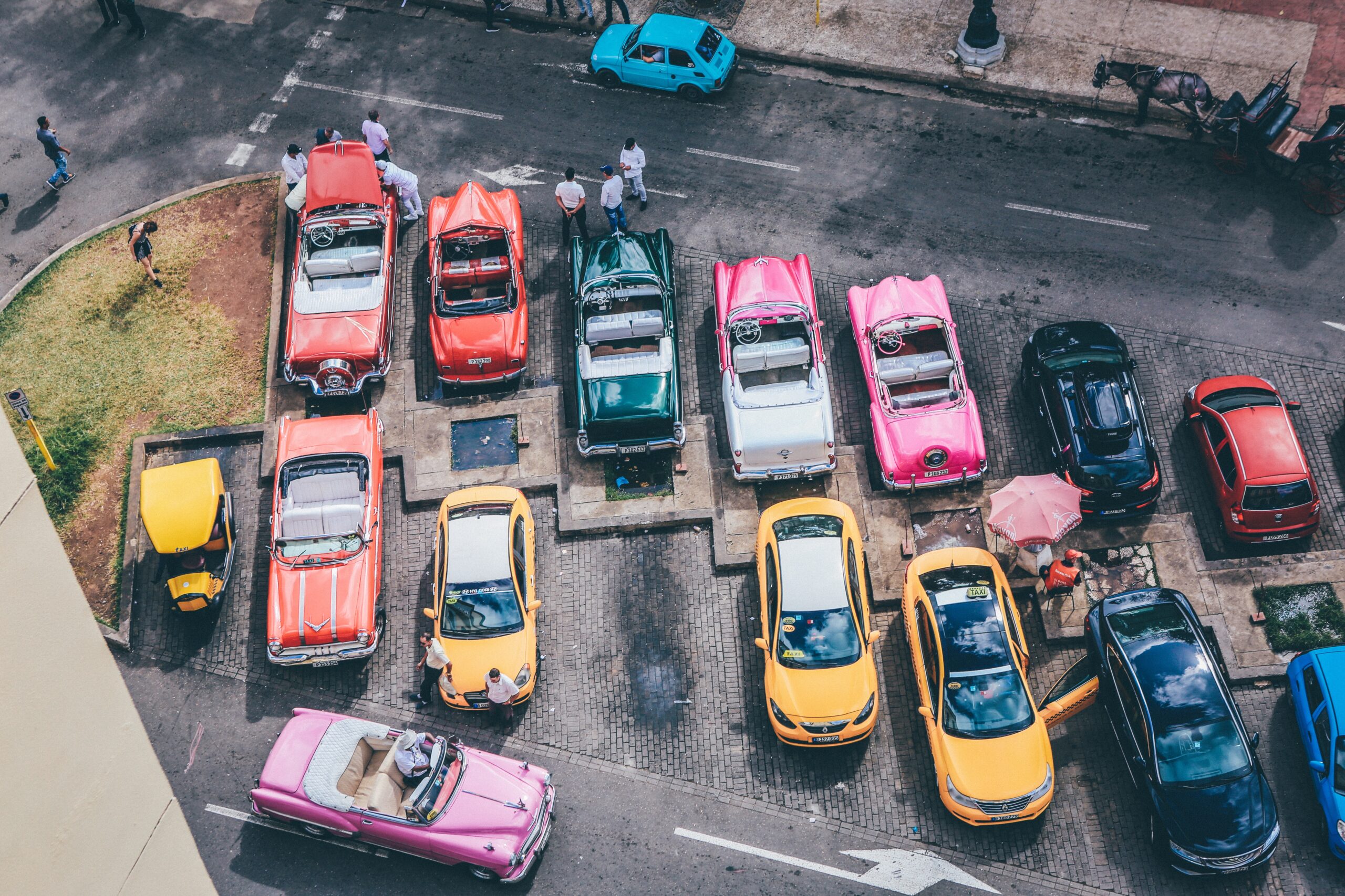 An overhead shot of assorted cars in different colors in a parking lot